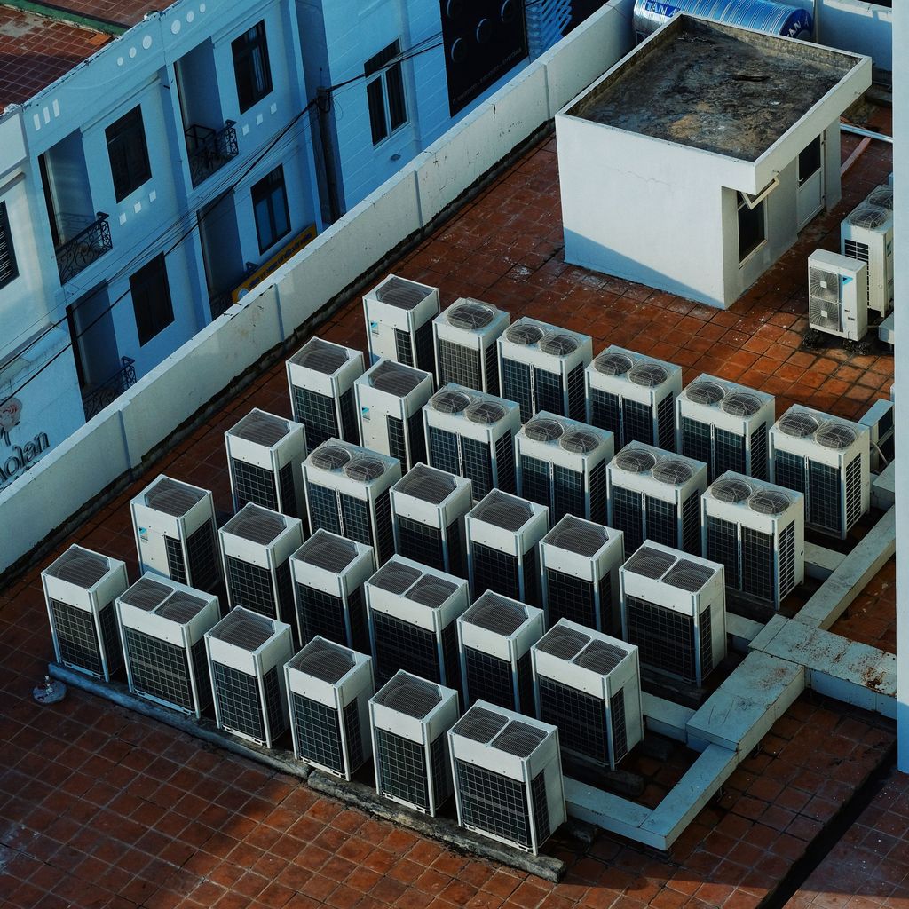 High-angle view of dozens of HVAC condensing units grouped on a flat roof