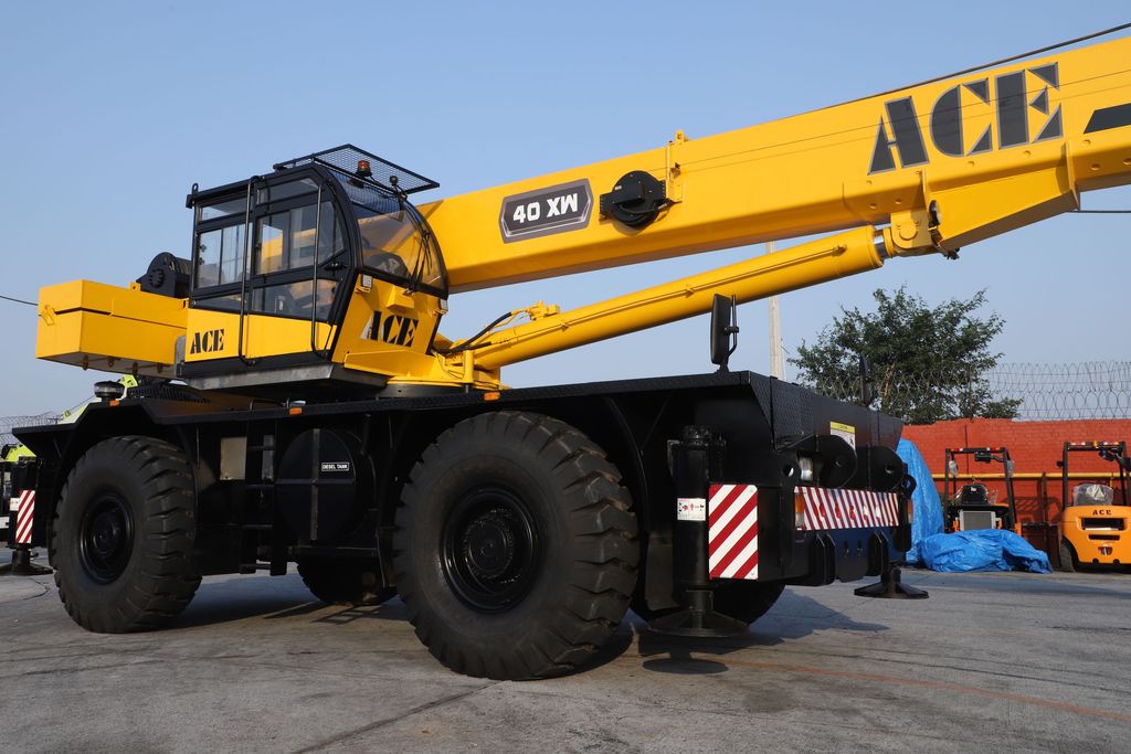 Close view of a yellow rough-terrain crane cab, boom, and large off-road tires